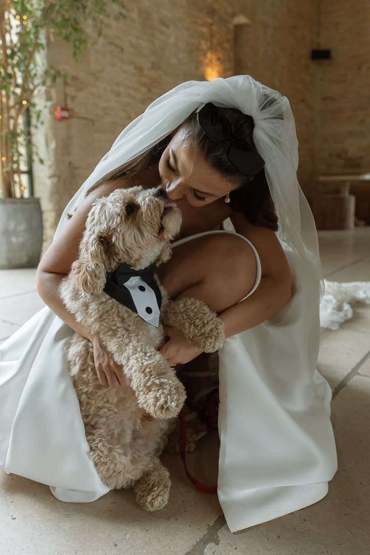 Bride in her veil kissing her Oodle wearing a black tuxedo bow tie
